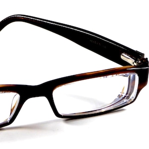 May include: Rectangular eyeglasses with a dark brown frame and clear lenses. The temples are solid black, and the frame has a tortoiseshell pattern near the lenses. The glasses are set against a white background.