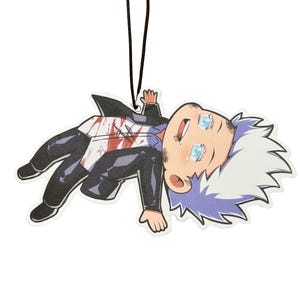 May include: Air freshener with a cartoon character design. The character has white and purple hair, blue eyes, and wears a black outfit. The character is lying down and smiling. Red accents are visible on the white shirt. A black string is attached.
