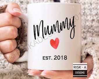 May include: White ceramic mug with black text that reads "Mummy" with a red watercolor heart and the text "EST. 2018".