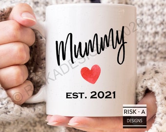 May include: White ceramic mug with black text that reads "Mummy Est. 2021" and a red watercolor heart.