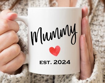 May include: White ceramic mug with black text that reads "Mummy Est. 2024" and a red watercolor heart.