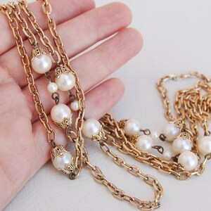 Puede incluir: Un collar de cadena dorada con m&uacute;ltiples hebras y detalles de perlas falsas.