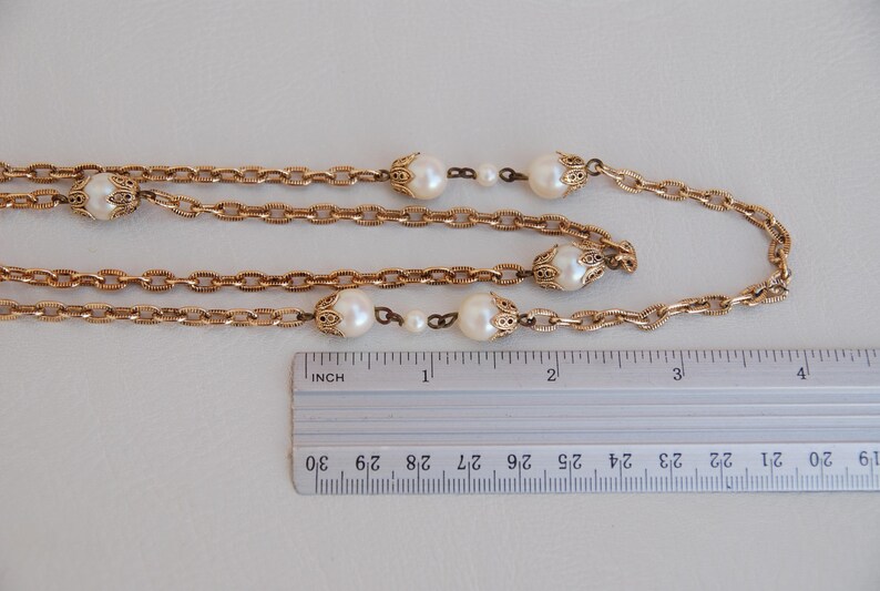 Puede incluir: Un collar de cadena dorada con detalles de perlas falsas. El collar mide aproximadamente 100 cm de largo y presenta un dise&ntilde;o de doble cadena.