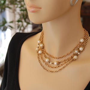 Puede incluir: Un collar de cadena de oro con m&uacute;ltiples hebras y acentos de perlas blancas.