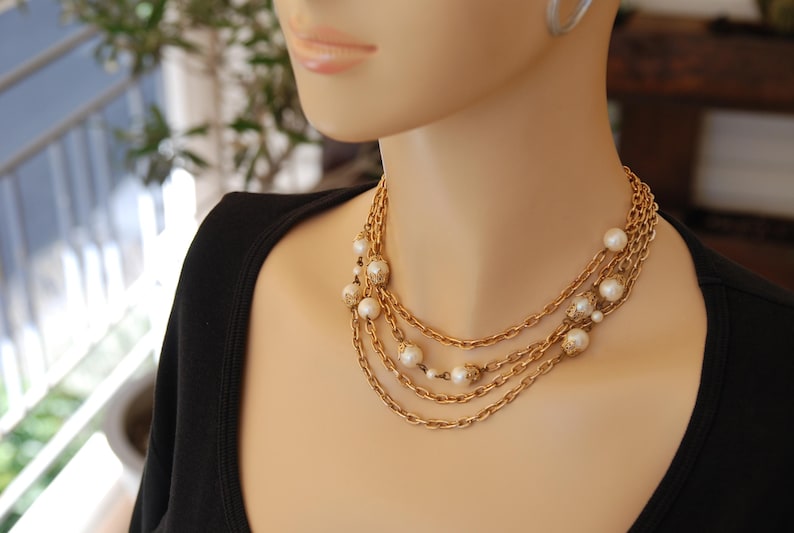 Puede incluir: Un collar de cadena de oro con m&uacute;ltiples hebras y acentos de perlas blancas.