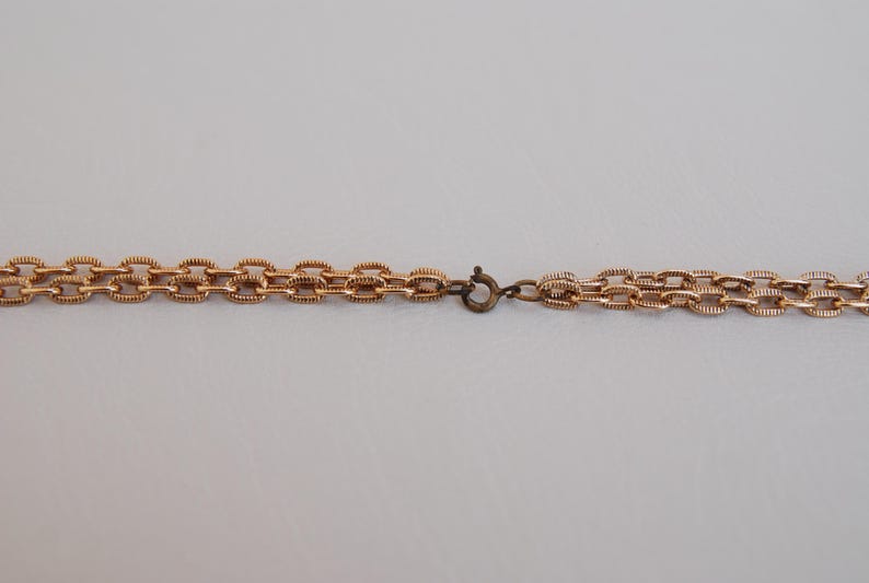 Puede incluir: Un collar de cadena de oro con cierre de broche.