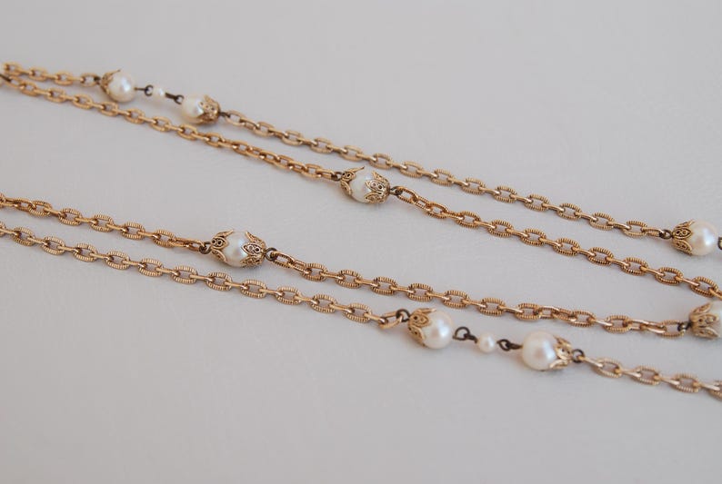 Puede incluir: Un collar de cadena de oro con m&uacute;ltiples hebras y detalles de perlas. Las perlas est&aacute;n engastadas en engastes de oro ornamentados.