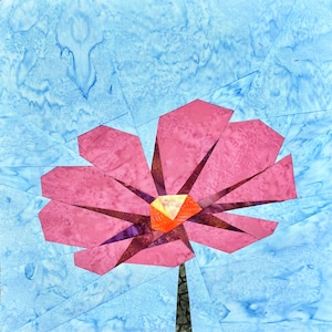 Puede incluir: Una flor de papel rosa con un centro amarillo sobre un fondo azul.