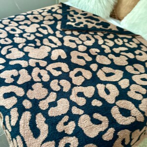 May include: A plush throw blanket with a black and brown leopard print pattern. The blanket is soft and fuzzy, perfect for cuddling up on the couch.