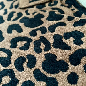 May include: A soft, plush throw blanket with a leopard print pattern in black and tan.