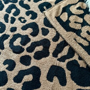 May include: A soft, plush throw blanket with a black and tan leopard print pattern.