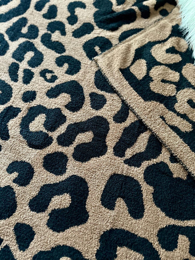 May include: A soft, plush throw blanket with a black and tan leopard print pattern.