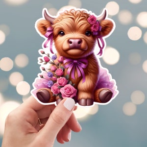 May include: A cute, brown and white Highland cow wearing a pink tutu and a pink bow. The cow is holding a bouquet of pink and purple flowers.