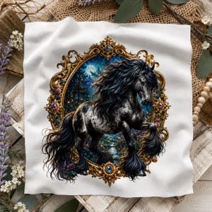May include: A white fabric square featuring a central ornate gold frame. Inside the frame is a black and white spotted horse with a long flowing mane and tail, set against a dark forest background with a full moon and a small glowing stream.