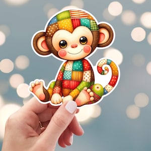 May include: A colorful patchwork monkey sticker with a brown face and big eyes. The monkey is sitting with its tail curled around its body.