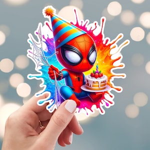 May include: A cartoon illustration of Spiderman wearing a party hat and holding a birthday cake with a single lit candle. The image is set against a colourful background of paint splatters.