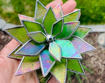 Puede incluir: Una suculenta de vidrio teñido verde iridiscente con un centro de metal plateado.