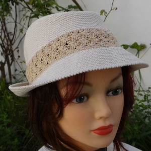 Handmade crocheted women&#39;s summer hat in ecru cotton with an openwork headband with beige flower pattern, soft, moldable, foldable and washable