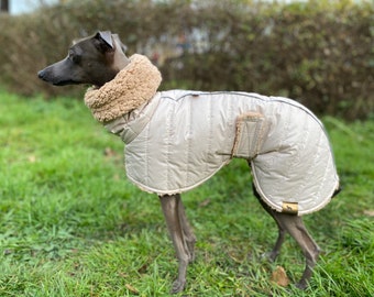 May include: A beige dog coat with a faux fur collar and a quilted design. The coat has a velcro closure and a small logo on the back.
