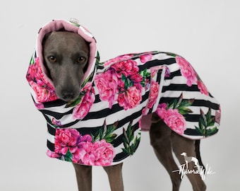 Könnte beinhalten: Ein grauer Italienischer Windhund trägt einen schwarz-weiß gestreiften Hundemantel mit einem rosafarbenen Blumenmuster. Der Mantel hat ein rosa Fleecefutter und eine Kapuze.