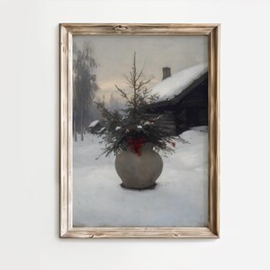 Könnte beinhalten: Gerahmtes Vintage-Winterlandschaftsgemälde. Eine große, runde, graue Vase enthält immergrüne Zweige und rote Beeren, eingebettet in eine verschneite Szene. Eine schneebedeckte Hütte und Bäume befinden sich im Hintergrund. Der Rahmen ist hellbraun.