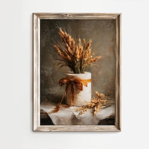 May include: A framed vintage-style print featuring a still life of wheat stalks in a white vase with an orange ribbon. The artwork has a neutral color palette with a rustic aesthetic, perfect for farmhouse decor.
