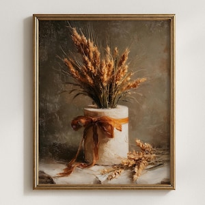 May include: A framed oil painting depicting a cylindrical white vessel filled with golden wheat stalks. A burnt orange ribbon is tied around the vessel in a bow. Additional wheat stalks lie on the surface next to the vessel against a dark background.