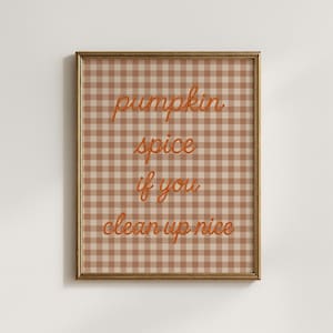 Può includere: Una stampa artistica da parete incorniciata con uno sfondo a quadretti vichy marrone chiaro e bianco. Il testo "pumpkin spice if you clean up nice" è scritto in un carattere corsivo arancione testurizzato, centrato nella cornice rettangolare.