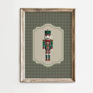 May include: A framed print featuring a Christmas nutcracker soldier. The nutcracker is dressed in a green and red uniform with a black hat and a red bow tie. The background is a plaid pattern in shades of green and brown.
