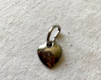 Silver metal pendant in the shape of a heart. Pendant with ring. Heart-shaped charm, love charm, silver grey. Metal pendant