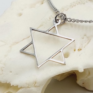 May include: A silver chain necklace with a silver pendant shaped like a six-pointed star. The pendant is on a white background.
