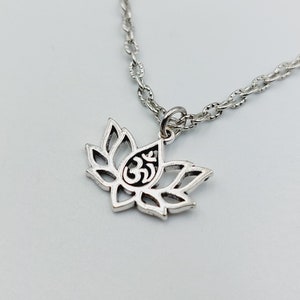 May include: A silver chain necklace with a pendant featuring a lotus flower with an Om symbol inside.
