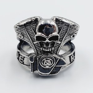 Könnte beinhalten: Ein silberner Ring mit einem Totenkopf- und Motor-Design. Der Ring trägt die Inschrift "Ride Free".