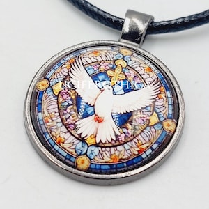 May include: A round pendant necklace featuring a white dove with outstretched wings centered on a circular stained glass pattern of blue, yellow, and orange hues. The pendant is set in a dark metal frame and hangs from a black cord.
