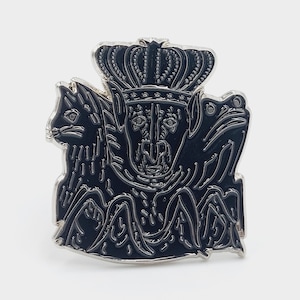 Pode incluir: Pin de esmalte preto com borda prateada. Apresenta uma criatura coroada ladeada por um coelho e um sapo. O design é colocado sobre um fundo branco, com detalhes intrincados.