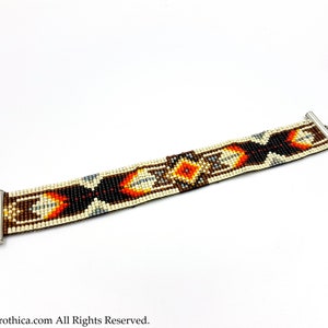 May include: A beaded bracelet with a geometric pattern in shades of brown, orange, white, and black. The bracelet has silver-toned clasps.
