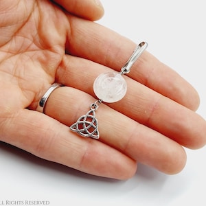 May include: A silver charm featuring a clear quartz crystal and a silver Celtic knot pendant.