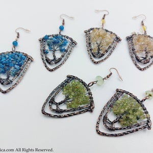May include: A set of six copper wire tree of life earrings featuring different coloured gemstones. The earrings are shaped like a triangle with a tree design in the centre. The gemstones are blue, green and yellow.