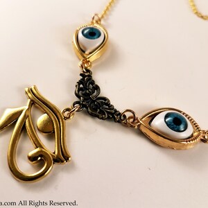May include: Gold chain necklace with three blue and white eye charms. The center charm is a gold Eye of Horus symbol.