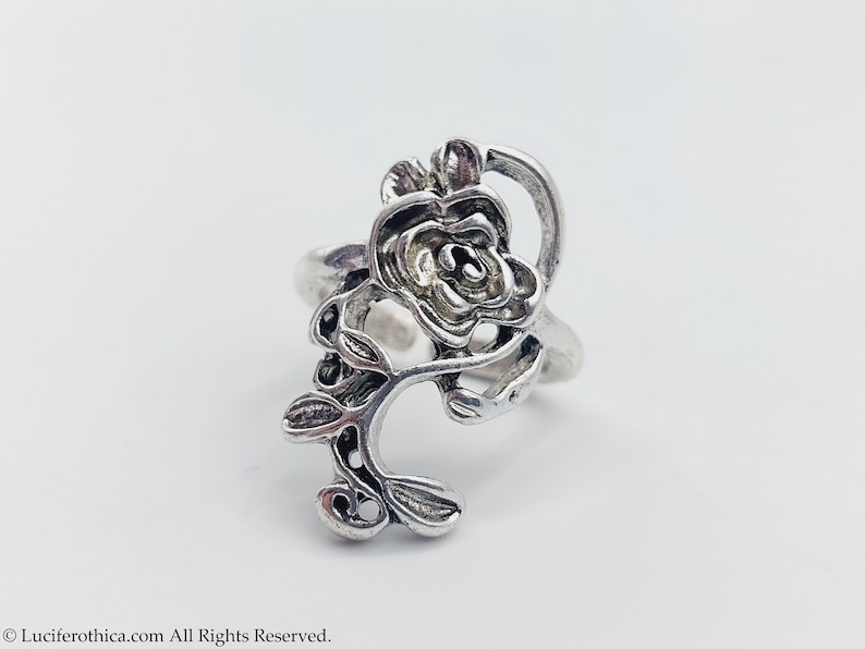 K&ouml;nnte beinhalten: Ein silberner Ring mit einem detaillierten Rosenmotiv. Die Rose sitzt auf einem Stiel mit Bl&auml;ttern.