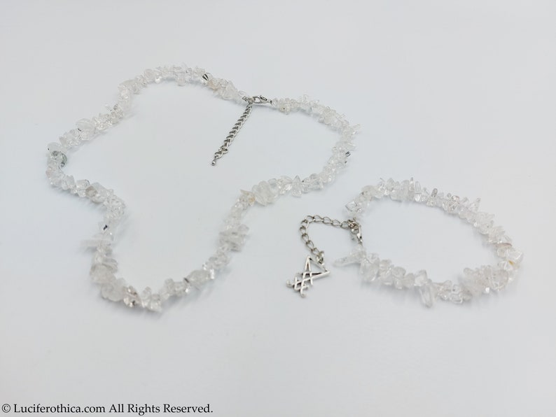 Puede incluir: Un conjunto de dos collares hechos con cristales de cuarzo transparentes. El collar m&aacute;s largo tiene un cierre plateado y el collar m&aacute;s corto tiene un dije plateado con un dise&ntilde;o geom&eacute;trico.