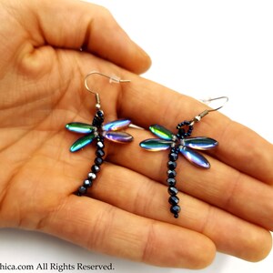 May include: A pair of iridescent dragonfly earrings with black beads hanging from silver hooks.