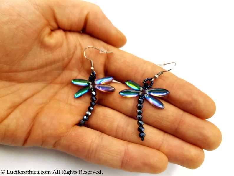 May include: A pair of iridescent dragonfly earrings with black beads hanging from silver hooks.