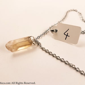 May include: A silver chain necklace with a clear quartz crystal pendant. The necklace has a tag with the number "4" written on it.