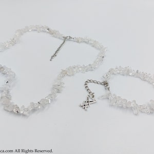 Puede incluir: Un conjunto de dos collares hechos con trozos de cuarzo transparente. El collar m&aacute;s largo tiene un dije de plata con un s&iacute;mbolo.