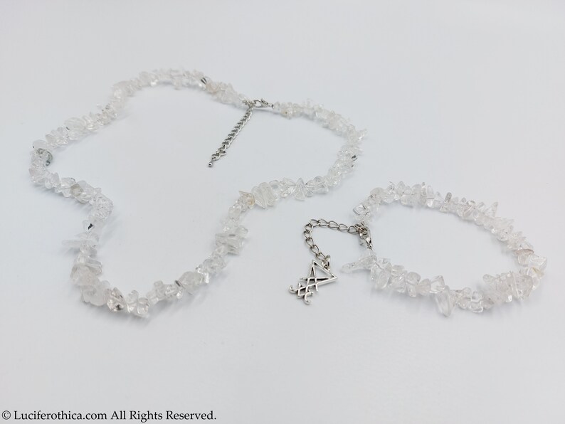 Puede incluir: Un conjunto de dos collares hechos con trozos de cuarzo transparente. El collar m&aacute;s largo tiene un dije de plata con un s&iacute;mbolo.