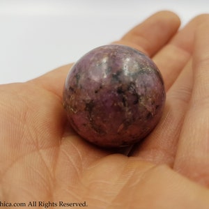 May include: A smooth, round, purple and black gemstone sphere.