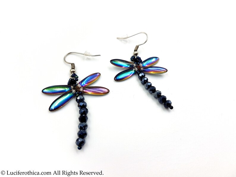 May include: A pair of iridescent dragonfly earrings with black crystal beads hanging from the bottom.