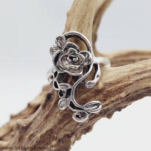 K&ouml;nnte beinhalten: Ein silberner Ring mit einem detaillierten Rosenmotiv. Die Rose ist aus filigraner, kunstvoller Metallarbeit gefertigt und hat eine Vintage-&Auml;sthetik.