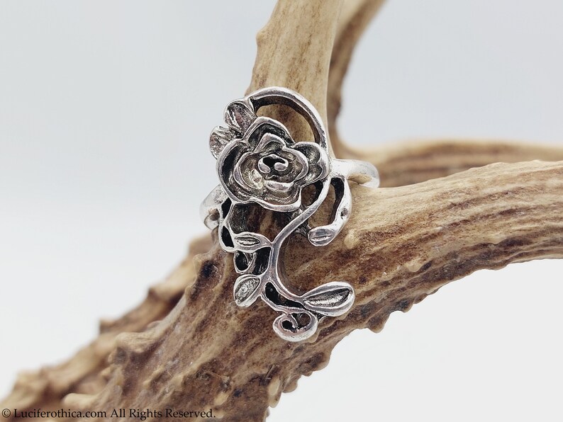 K&ouml;nnte beinhalten: Ein silberner Ring mit einem detaillierten Rosenmotiv. Die Rose ist aus filigraner, kunstvoller Metallarbeit gefertigt und hat eine Vintage-&Auml;sthetik.